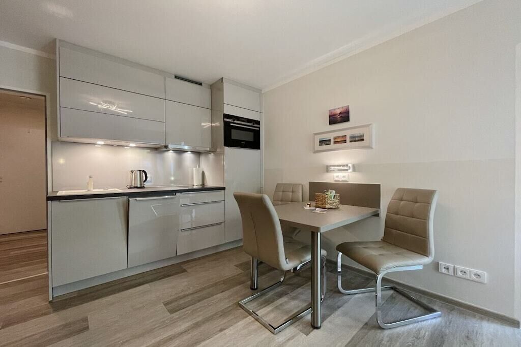 Cozinha moderna com área de jantar, com mesa e cadeiras, e forno embutido.