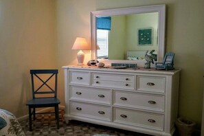 A bedroom with a white dresser, a chair, a lamp, and a mirror. - Holiday home with 2 bedrooms (St. Augustine)