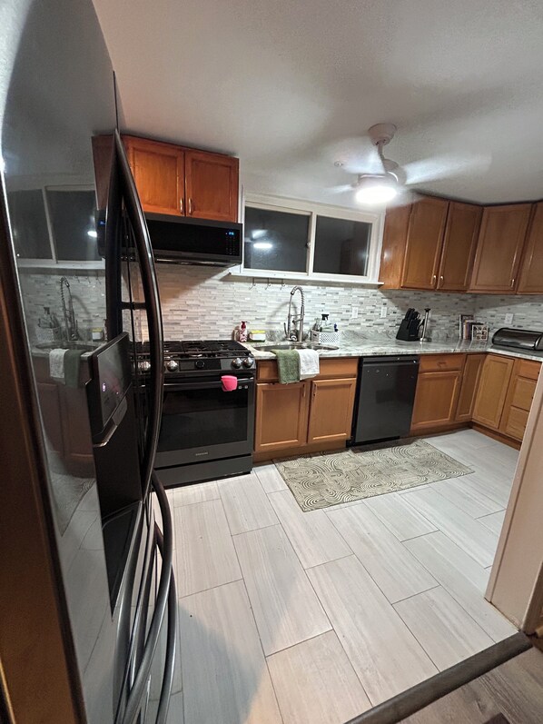 A kitchen with wooden cabinets, a stainless steel sink, a microwave, and a stove.