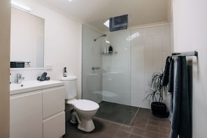 Een moderne badkamer met toilet, wastafel en douche.