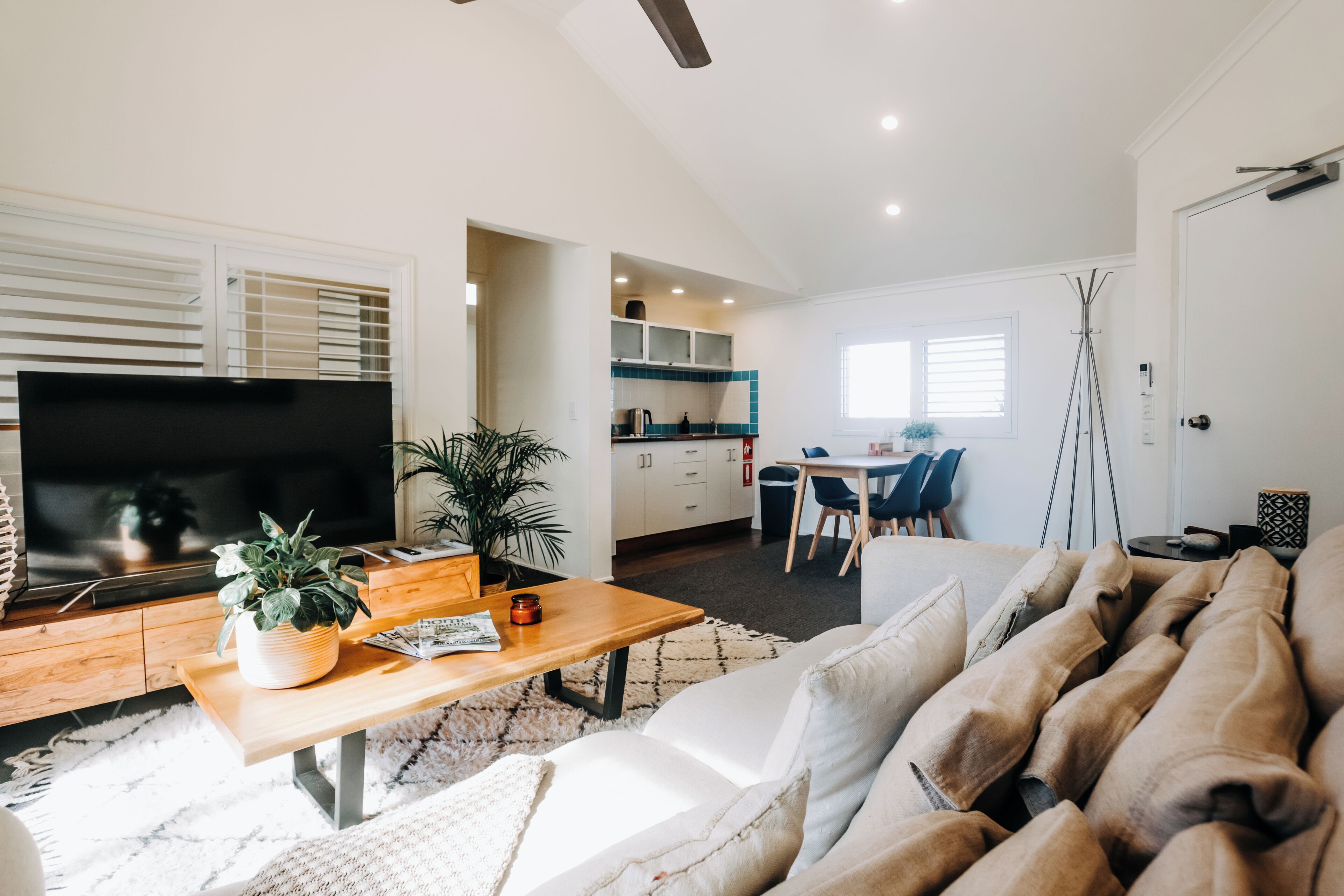Una sala moderna con un televisor de pantalla plana, una mesa de centro de madera y un sofá color beige.