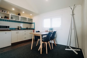 Een moderne keuken met witte kasten, een houten tafel en zwarte stoelen.