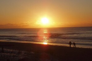 A sunset over the ocean with two silhouettes of people on the beach. - Holiday home with 2 bedrooms (Callantsoog)