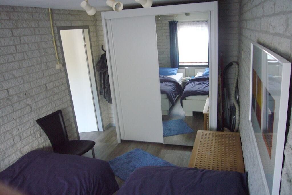 A room with a bed, a chair, a mirror, and a wardrobe.