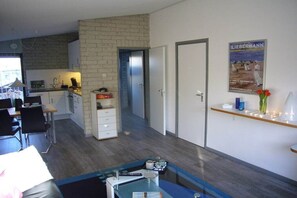 A modern living room with a dining area, a kitchen, and a door leading to another room. - Holiday home with 2 bedrooms (Callantsoog)