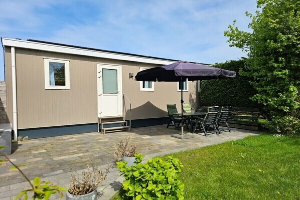 A mobile home with a patio area featuring a table and chairs, a door, and a window. - OK40 Chalet Oostkapelle (Oostkapelle)