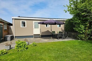 Una casa móvil con un patio, mobiliario exterior y un jardín.