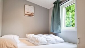 A single bed with white bedding in a room with a window and a picture on the wall. - OK40 Chalet Oostkapelle (Oostkapelle)