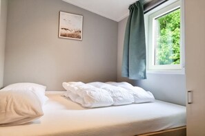 A single bed with white bedding in a room with a window and a picture on the wall. - OK40 Chalet Oostkapelle (Oostkapelle)