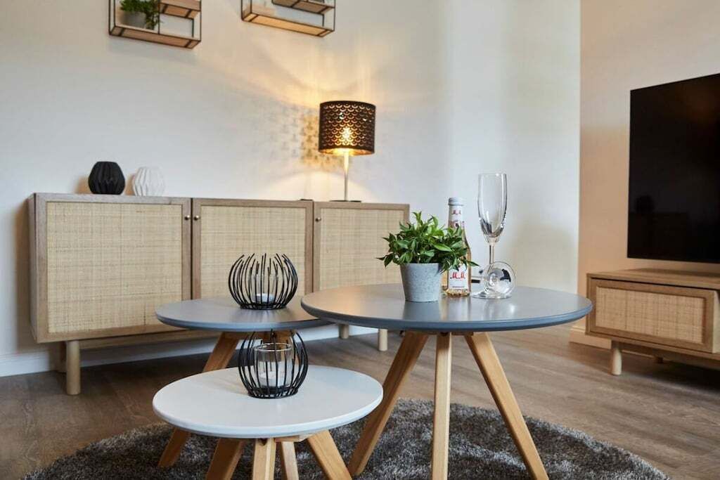 A modern living room with a sofa, two round tables, a floor lamp, and a television.
