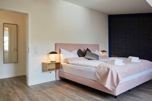 A modern bedroom with a bed, bedside tables, and a mirror. - Nautimar Apartment Kattegat 32 (Büsum)