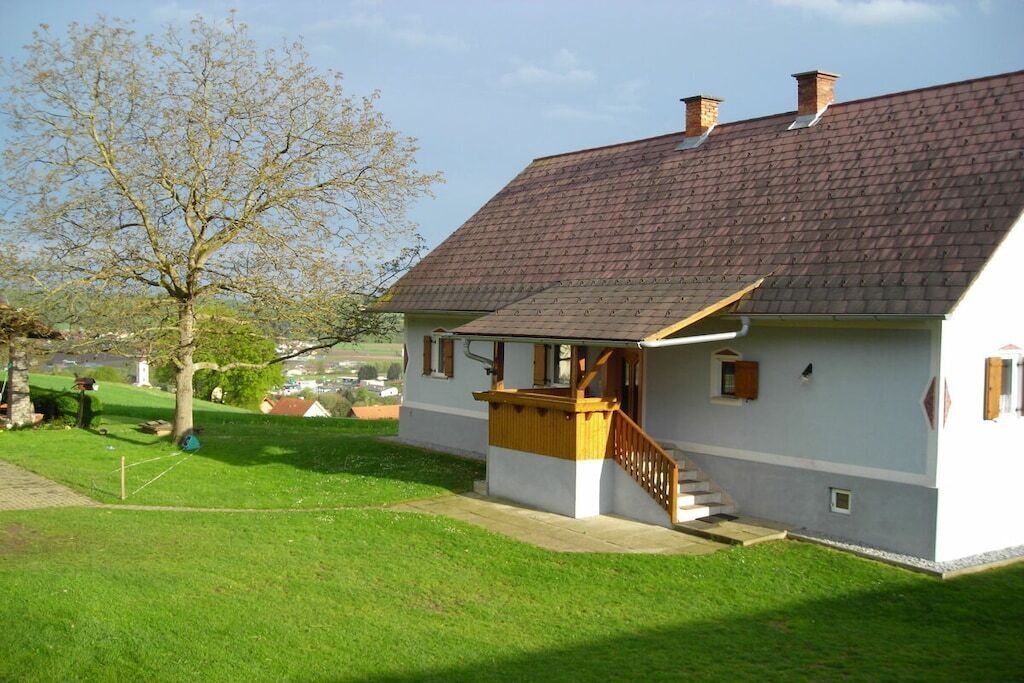 A single-story house with a sloped roof, a wooden staircase leading to a porch, and a well-maintained lawn.