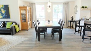 A dining area with a long table and chairs, a cabinet with glass doors, and a sofa with cushions. - Holiday home in Glowe with swimming pool (Glowe)