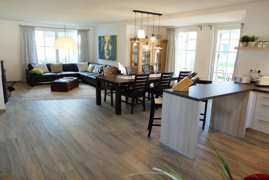 Ein modernes Wohnzimmer mit Sofa, Esstisch und Küchenbereich.