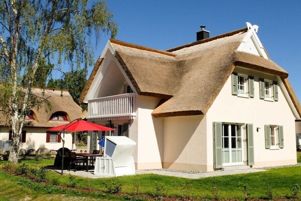 Une maison avec un toit à forte pente, un balcon et un parasol rouge.