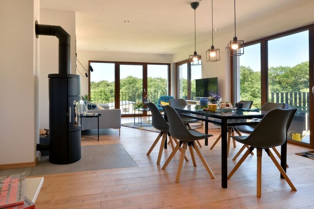 A modern dining area with a large table, chairs, and a black stove.
