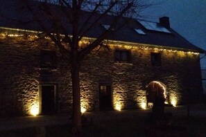 Un edificio de piedra con múltiples ventanas y puertas, iluminado por luces cálidas.