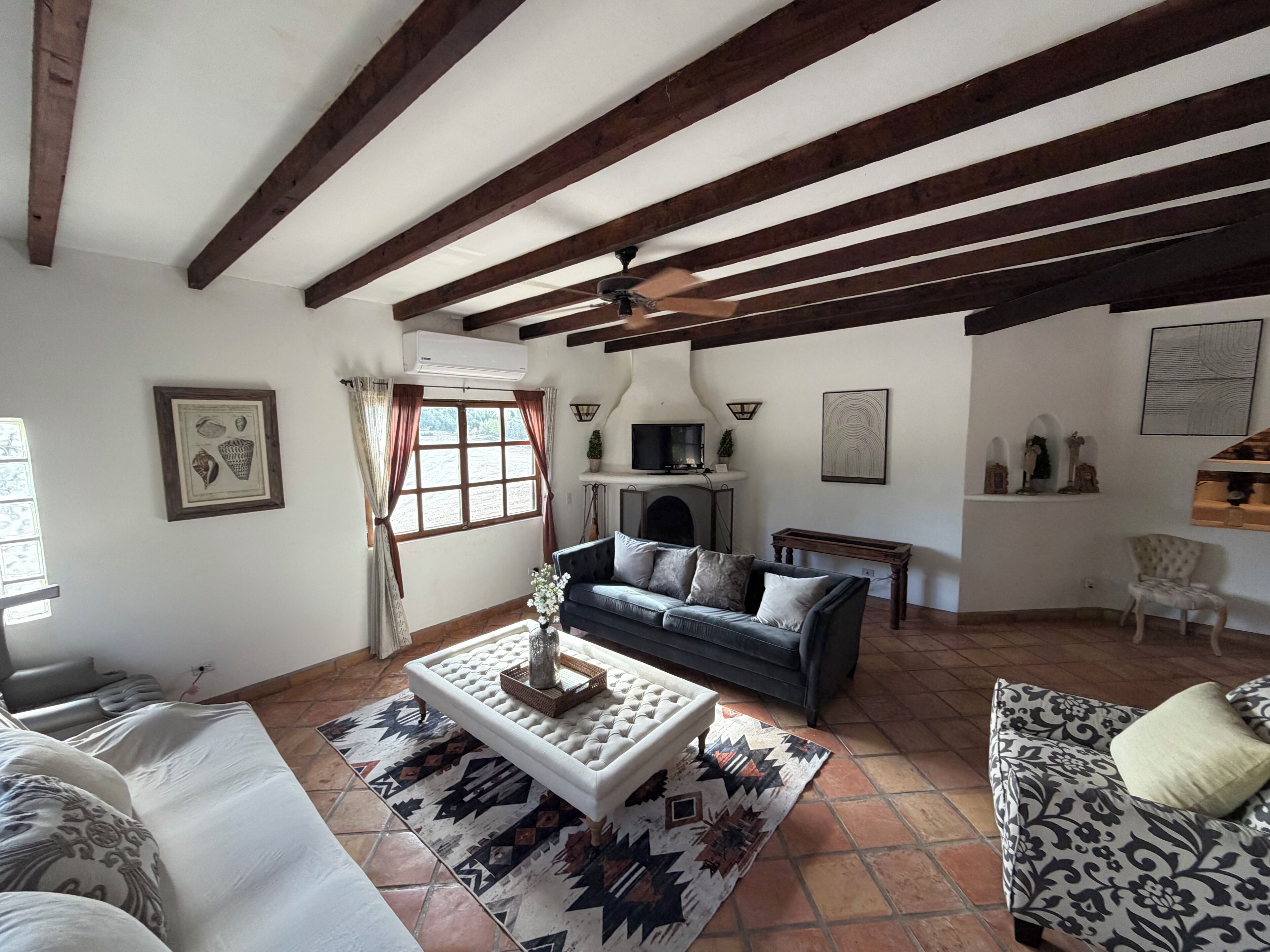 Sala de estar com lareira, sofá, tapete estampado e ventilador de teto.