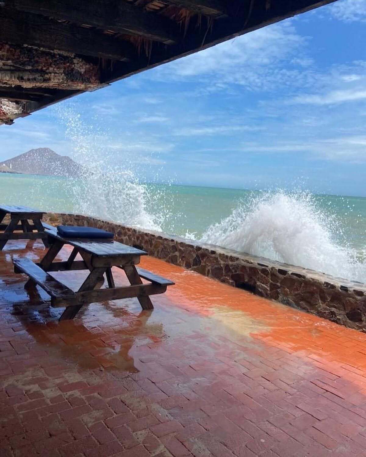 Uma área de estar à beira-mar com um muro de pedra e um banco de madeira.