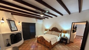 Ein Schlafzimmer mit einem hölzernen Bett, zwei Nachttischlampen, einem Deckenventilator und einem Fliesenboden.