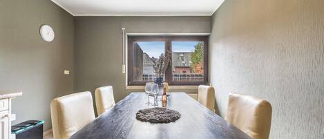 A dining area with a long table, chairs, and a view through a window.
