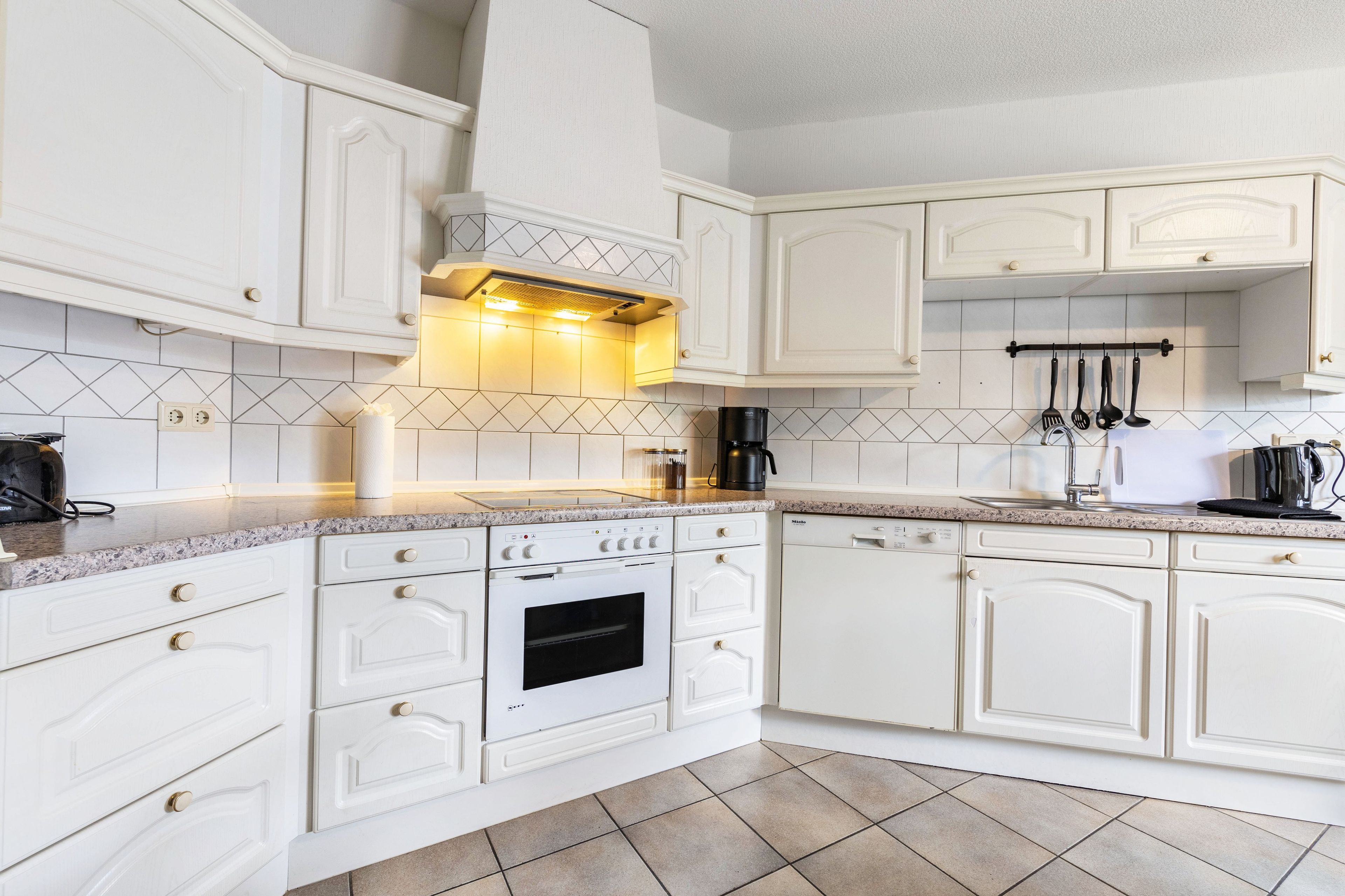 A modern kitchen with white cabinetry, a built-in oven, and a coffee maker.