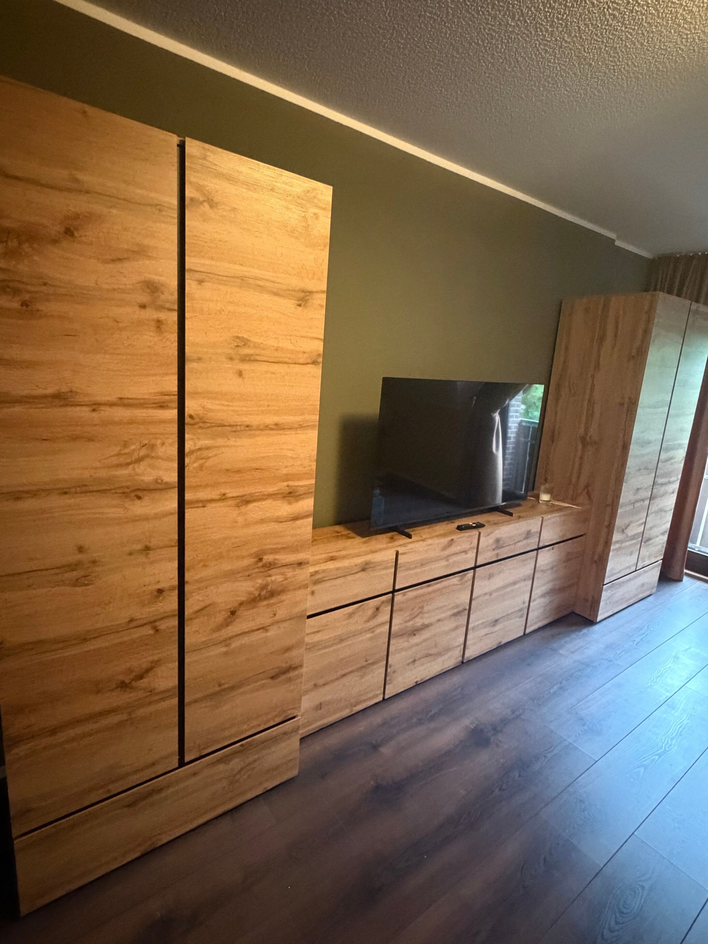 Ett rum med ett träskåp, en tv ovanpå och ett stort fönster.