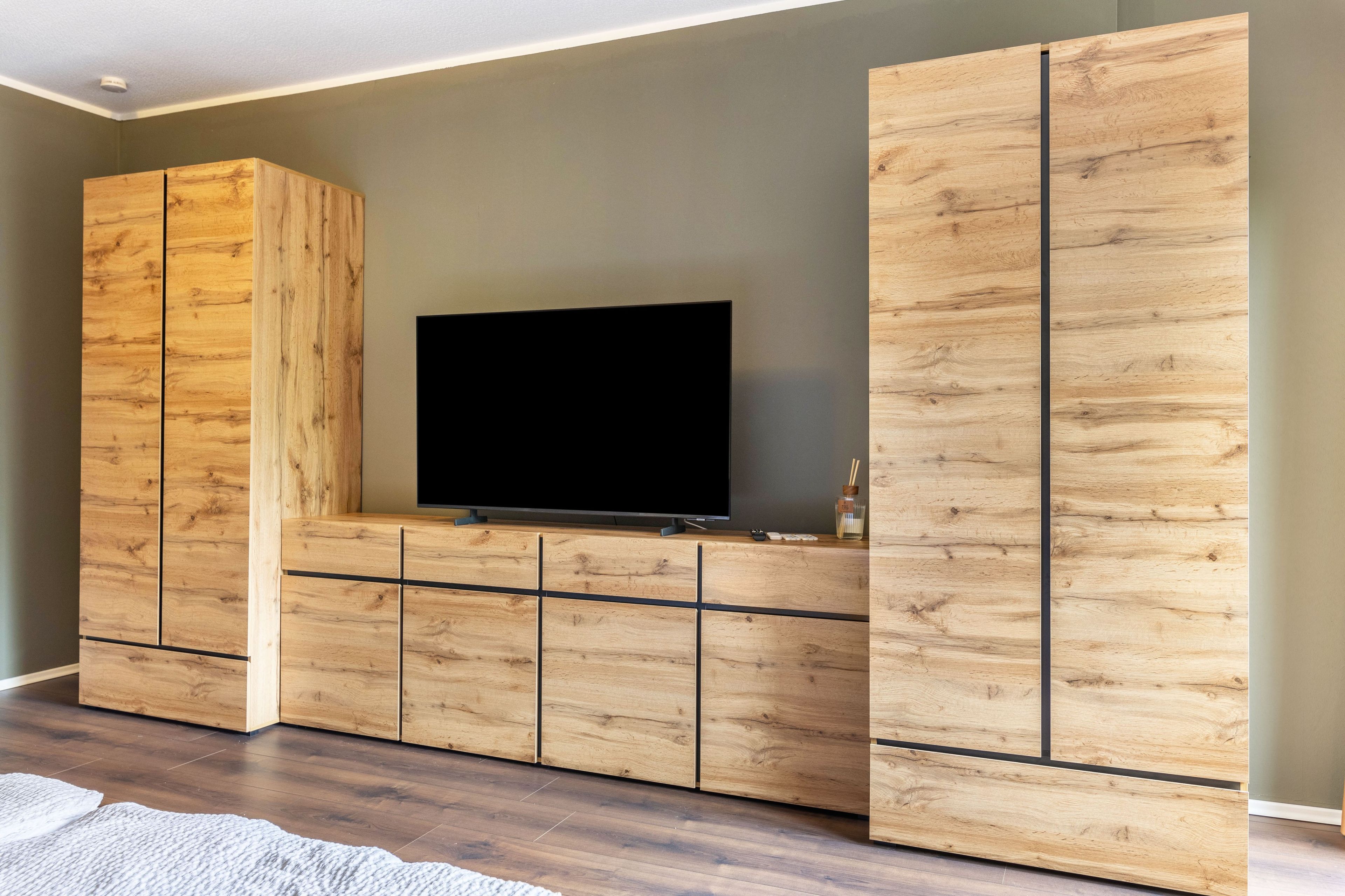 Ein modernes Wohnzimmer mit einem flachbildfernseher, der an einem Holzkabinett befestigt ist.