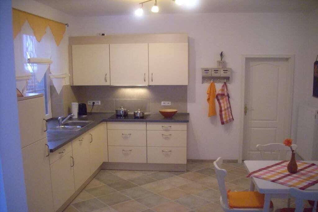 Een keuken met een spoelbak, kastjes en een tafel met stoelen.