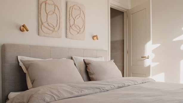A bedroom with a bed, headboard, and two wall art pieces.