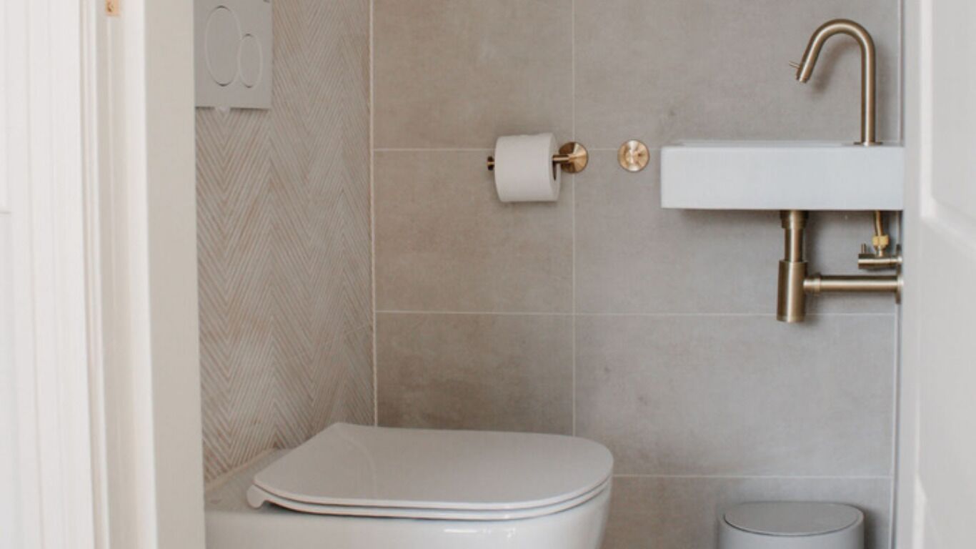 Een badkamer met toilet, wastafel en een vuilnisbak.