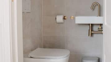 Een badkamer met toilet, wastafel en een vuilnisbak.