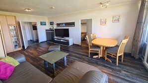 Un saló modern amb un sofà, una taula baixa i una zona de menjador amb cadires i taula.