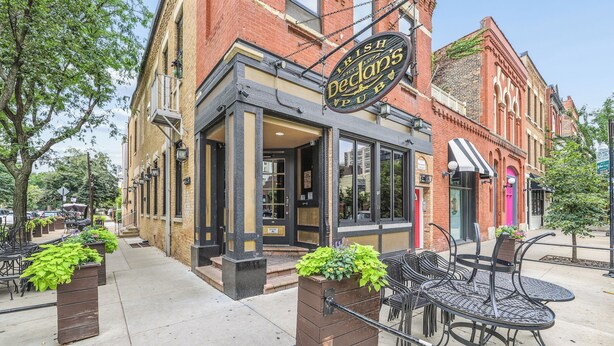 A brick building with a sign for 'Irish Declans' Pub' and outdoor seating with metal chairs and tables. - Scott C.H. (Chicago)