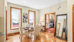 A dining area with a wooden table and chairs, a large mirror, and a kitchen visible through an open doorway. - Scott C.H. (Chicago)