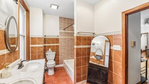 Une salle de bain comprenant des toilettes, un lavabo, une baignoire et un meuble-lavabo avec un miroir.