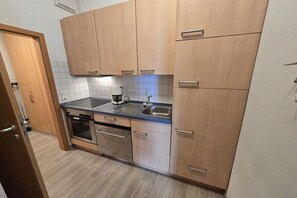 Eine Küche mit Holzausstattung, einer Edelstahl-Spüle und einem eingebauten Ofen.