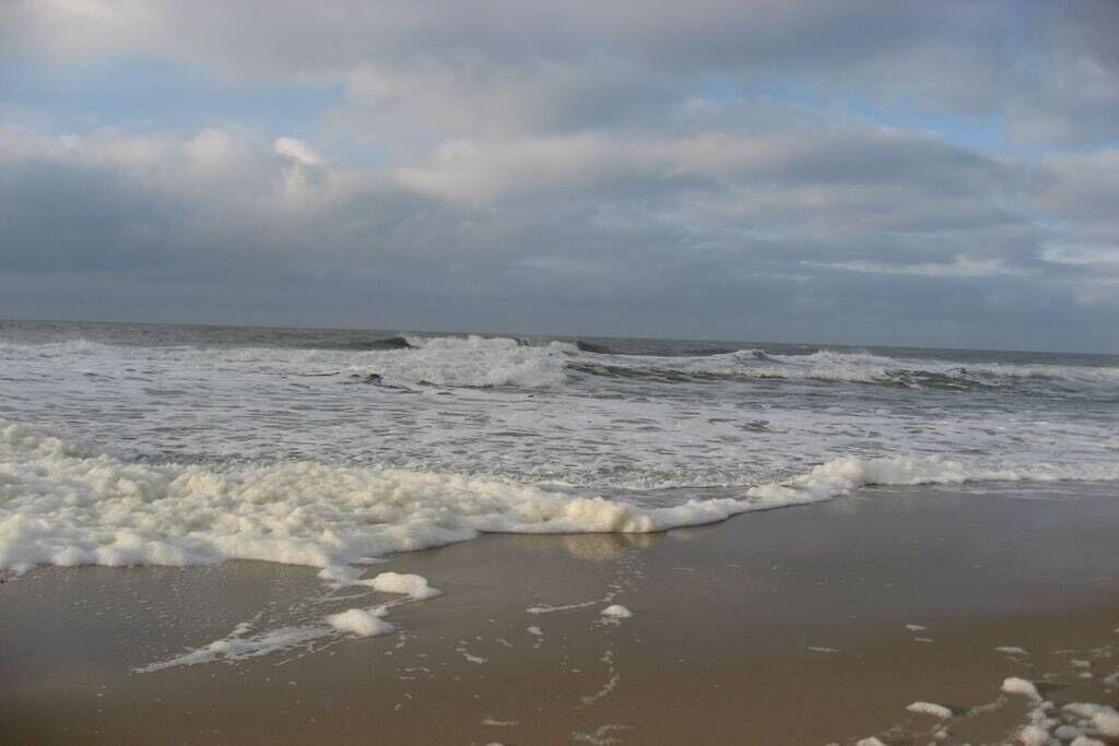 Una spiaggia con onde e schiuma sulla riva.