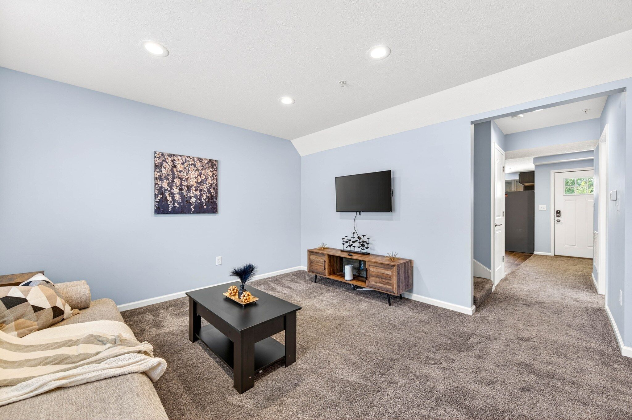 A living room with a sofa, a coffee table, a flat-screen TV, and a decorative piece on the wall.