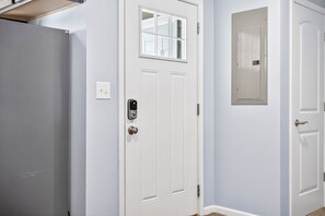 A white door with a window, a light switch, and a doorbell.