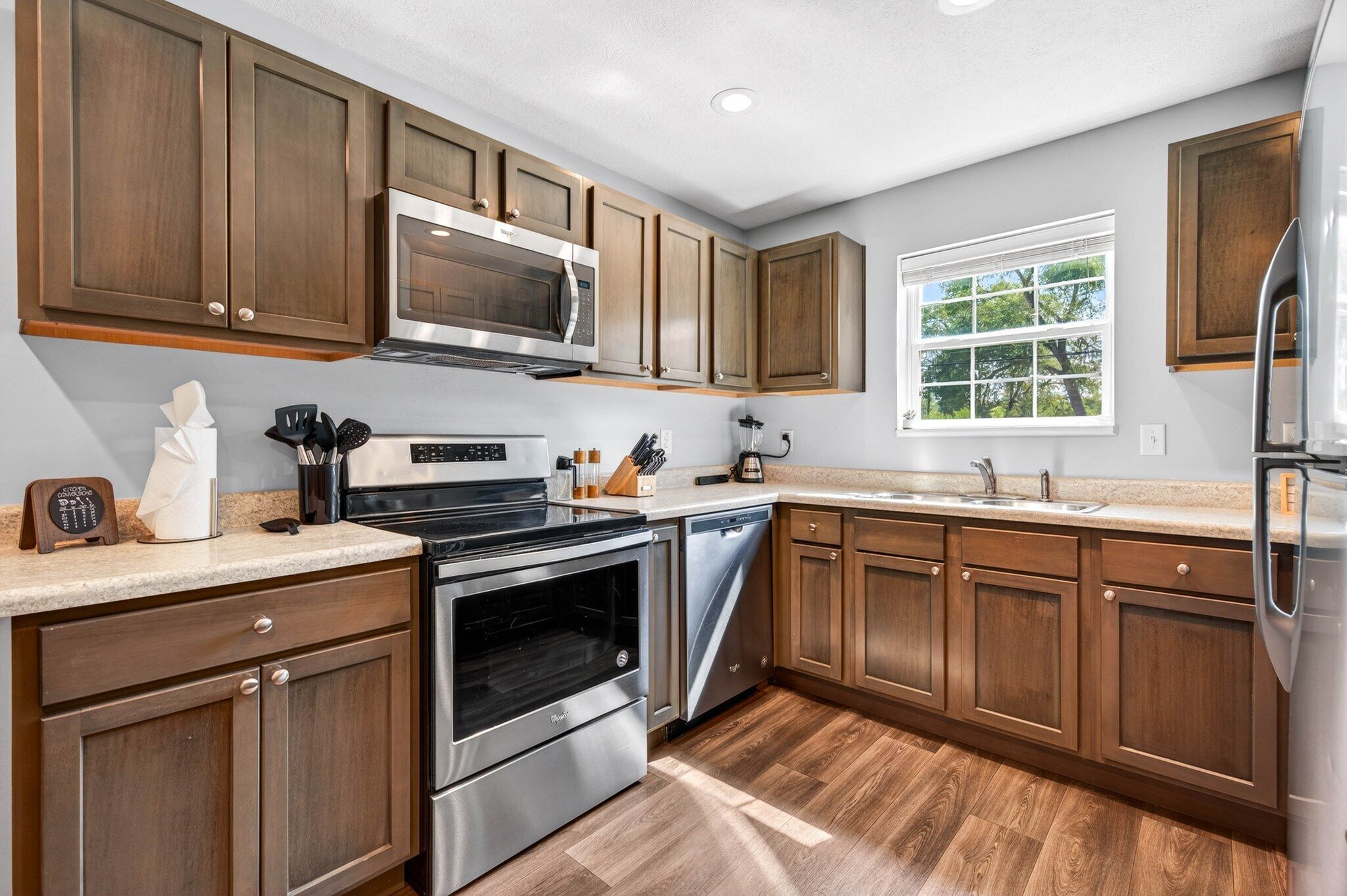 A modern kitchen with wooden cabinets, stainless steel appliances, and a window providing natural light.