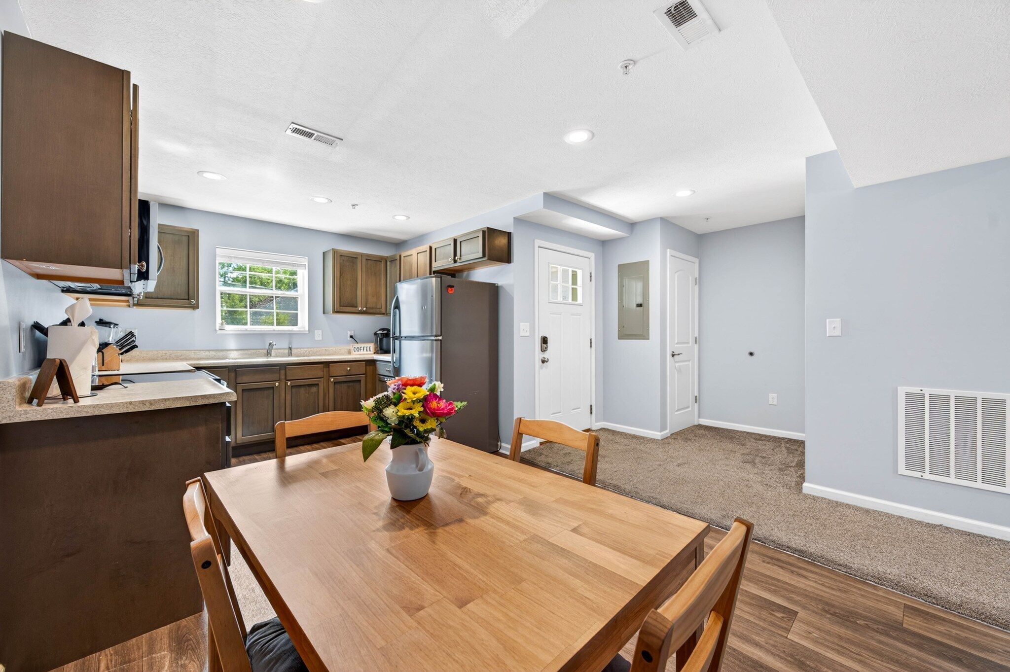 A modern kitchen with wooden cabinets, a refrigerator, and a window.