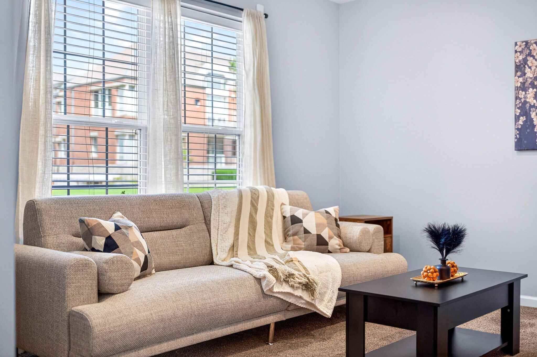A living room with a sofa, a coffee table, and a window with blinds.