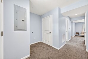 A hallway with carpeted floors, light blue walls, and white doors.