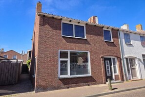 A two-story brick house with a front door, a small porch, and a window. - Holiday home in Domburg with swimming pool (Domburg)