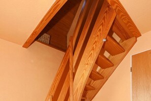 A wooden staircase with a handrail, leading to a higher floor. - Holiday apartments "Robbe" (Esens-Bensersiel)