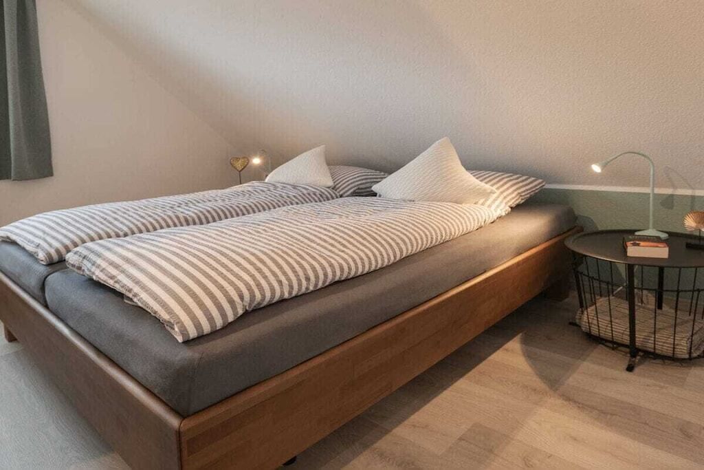 A modern bedroom with a bed, bedside lamps, and a small round table.