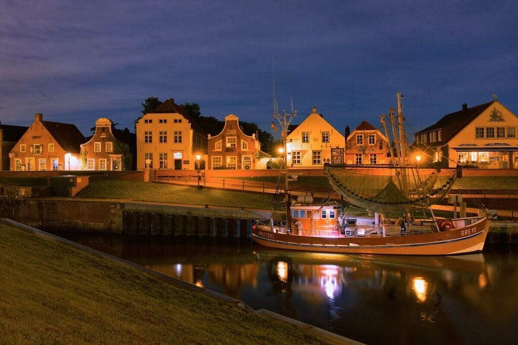 Une propriété située au bord de l’eau, avec un bateau amarré, un canal et des bâtiments traditionnels aux couleurs chaleureuses.