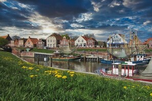 A waterfront scene with boats docked, a canal, and traditional buildings. - Holiday apartment with 1 bedroom (Greetsiel)