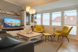 Un salon moderne avec un téléviseur à écran plat, des fauteuils jaunes, une table basse et un canapé.